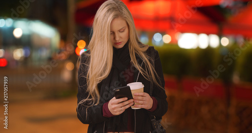 Pretty white female checks social media on phone after getting some coffee