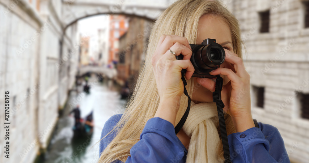 Beautiful Caucasian tourist with digital camera taking photos around Venice