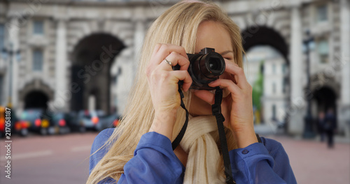Traveling young white woman takes pictures near Admiralty Arch in London