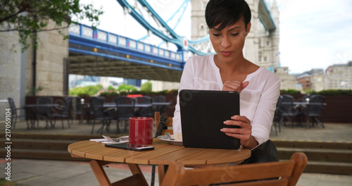 Photography Mixed race female drinking coffee while using tablet near Tower Bridge in London