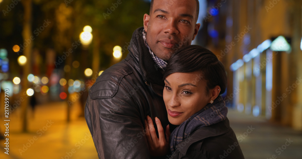 African man and woman hold each other tightly on Champs-Elysees 