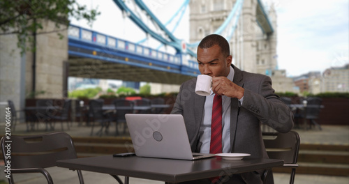 Photography African businessman working on laptop while drinking coffee at London cafe
