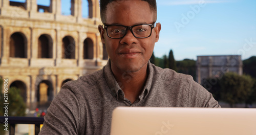 Photography Portrait of happy African American man sitting with laptop near Coliseum