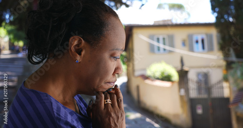 Elderly black woman standing outside praying photo