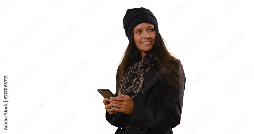 Pretty Caucasian female in hat and scarf texting on white background