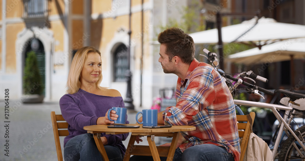 Couple chatting and drinking coffee outdoors in Italy