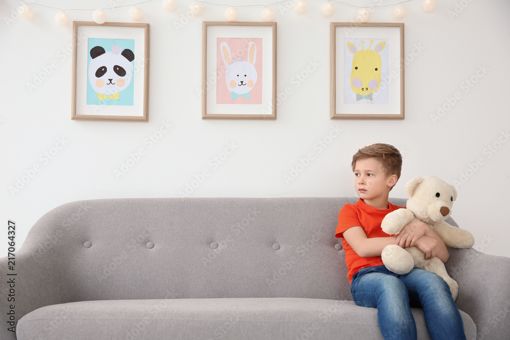 Little autistic boy sitting on sofa with toy at home Little autistic boy sitting on sofa with toy at home
