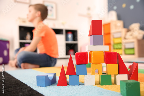 Castle made from cubes and little boy with autistic disorder on background