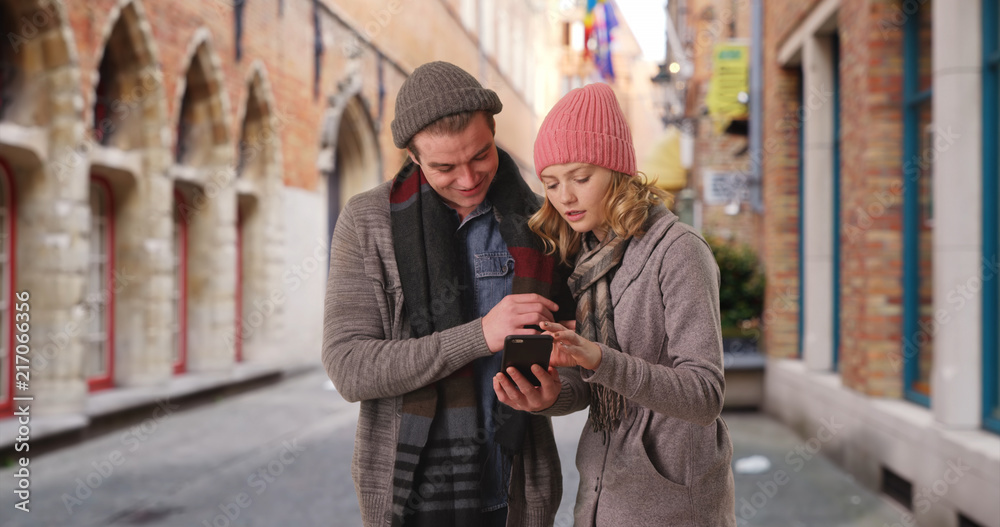 Fototapeta premium Attractive male and female using smartphone for directions on Belgian streets