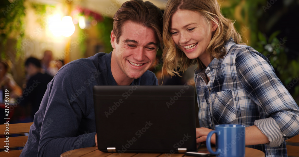 Cheerful man and woman watching video on laptop smiling and laughing