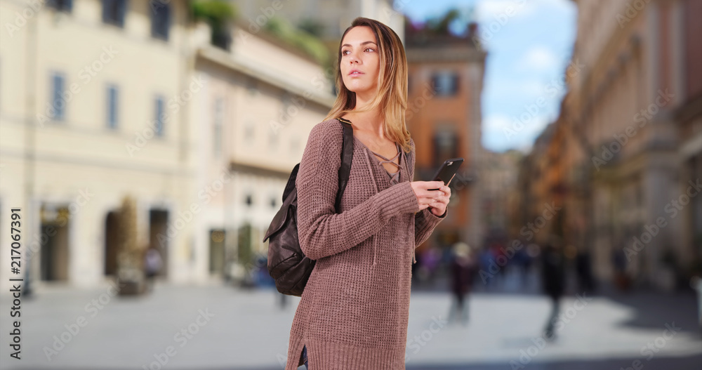 Woman walks down Rome street using map on smartphone for directions Woman walks down Rome street using map on smartphone for directions