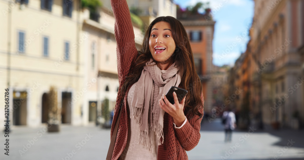 Fototapeta premium Pretty Latina woman with her phone smiling and saying hi