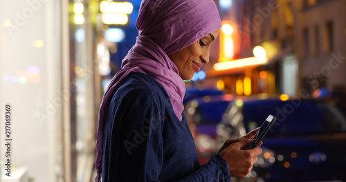 Young Muslim woman on urban street at night texting © rocketclips