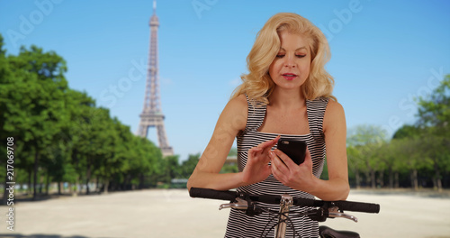 Beautiful woman with her bike uses app on mobile phone for directions