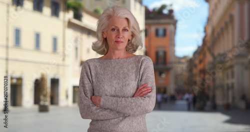 Confident woman tourist standing with arms crossed in Rome while on vacation photo