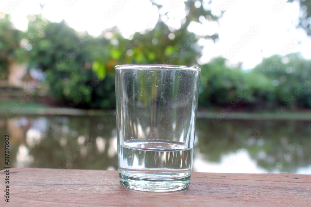 Close up pouring purified fresh drink water from the bottle on wooden table with nature background Close up pouring purified fresh drink water from the bottle on wooden table with nature background