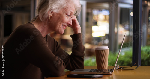 Happy older woman browsing internet in coffee shop with wifi