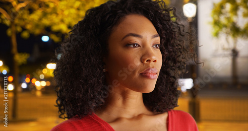 Nonchalant black woman staring off into distance outside on Paris sidewalk photo