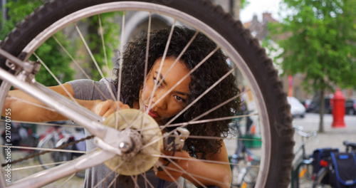 Close up of African woman fixing wheel or tire on bike while in city square
