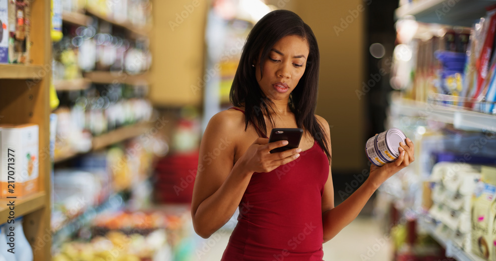 Black woman at the supermarket checking nutritional facts using app on cellphone
