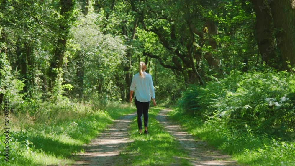Blonde woman walking through lush woods, SLOWMO ZOOM IN Blonde woman walking through lush woods, SLOWMO ZOOM IN