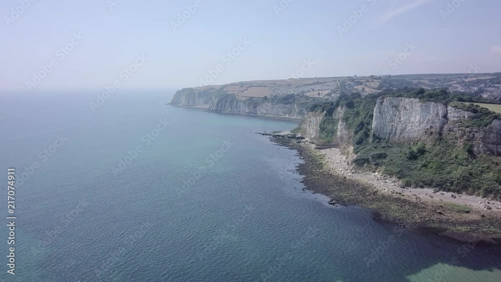 Flying next to the beach of the coastal town of Seaton in England. On the right are the cliffs and rock formations. The sand can be seen below, the woodland above. The sky view is amazing. Flying next to the beach of the coastal town of Seaton in England. On the right are the cliffs and rock formations. The sand can be seen below, the woodland above. The sky view is amazing.