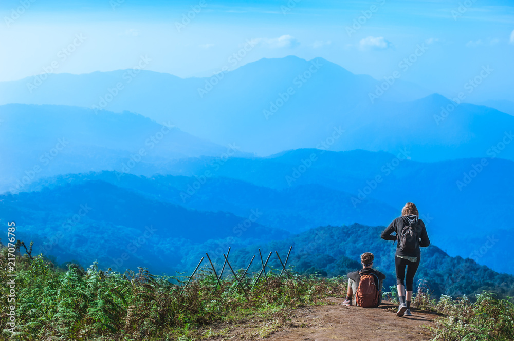 Couple Travelers Man and Woman with backpack sitting relaxed on mountain