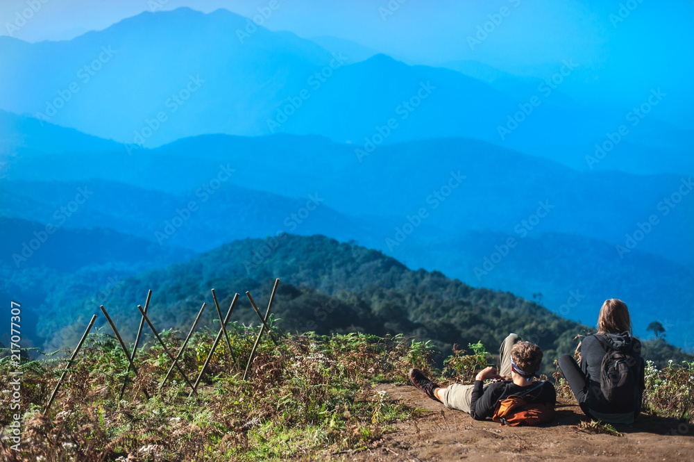 Fototapeta premium Couple Travelers Man and Woman with backpack sitting relaxed on mountain