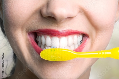 Female brushing teeth with yellow brush