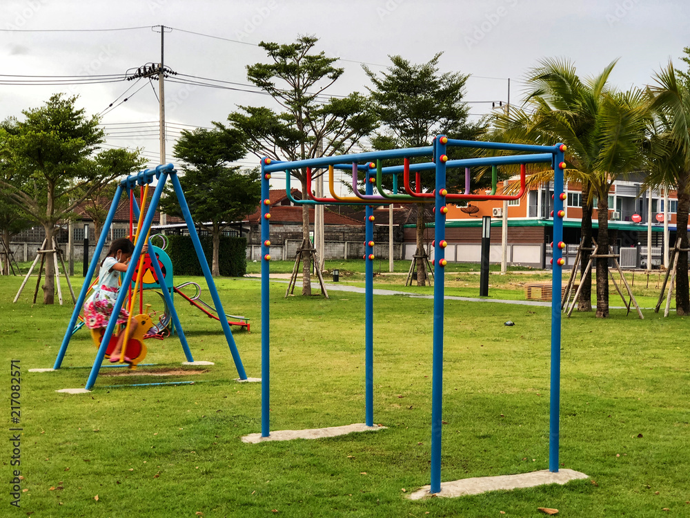 a girl play yellow swing shape duck Set in a playground with green grass. Funny time.