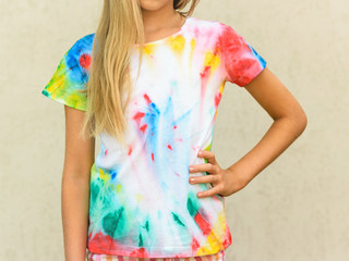 Girl at the wall in a t-shirt painted in the style of tie dye.