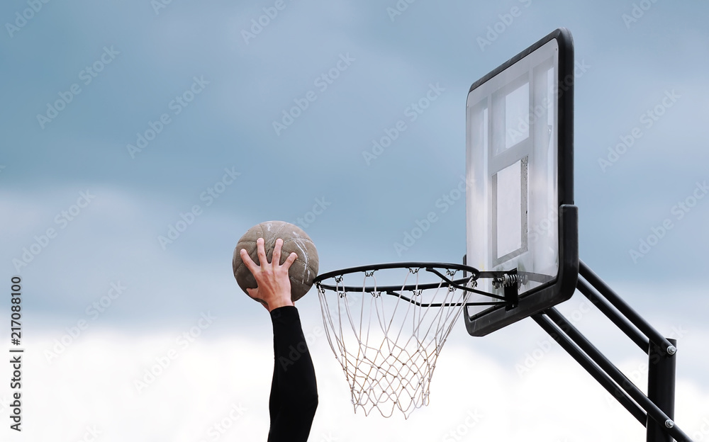 Fototapeta premium The hand of the basketball player throws a ball into a ring