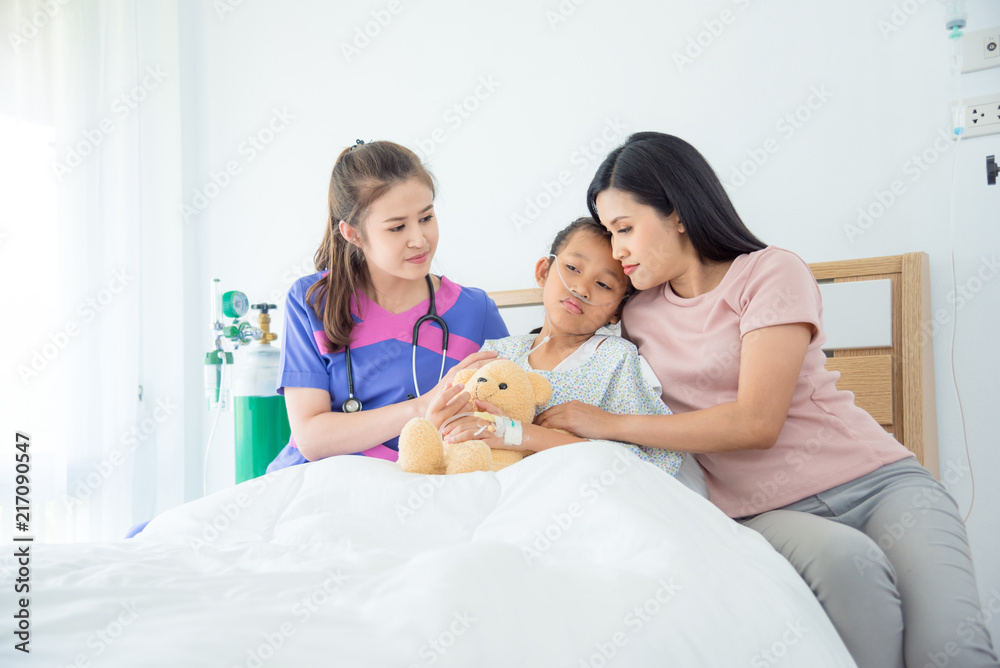 Young asian female doctors visiting child patient on ward Young asian female doctors visiting child patient on ward