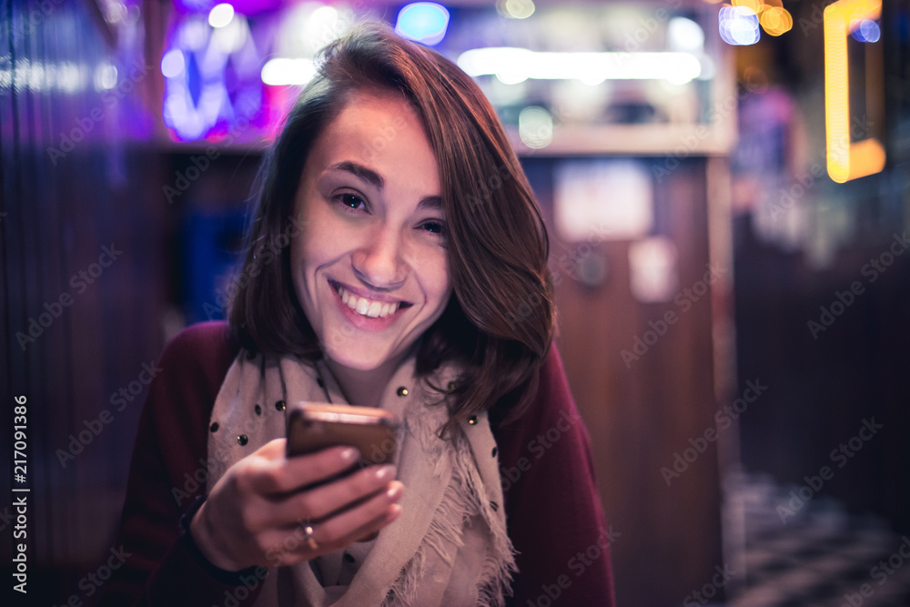 A happy girl a using your cellphone in a bar. This photo represents social interactions, technology in social world and a comum social life A happy girl a using your cellphone in a bar. This photo represents social interactions, technology in social world and a comum social life