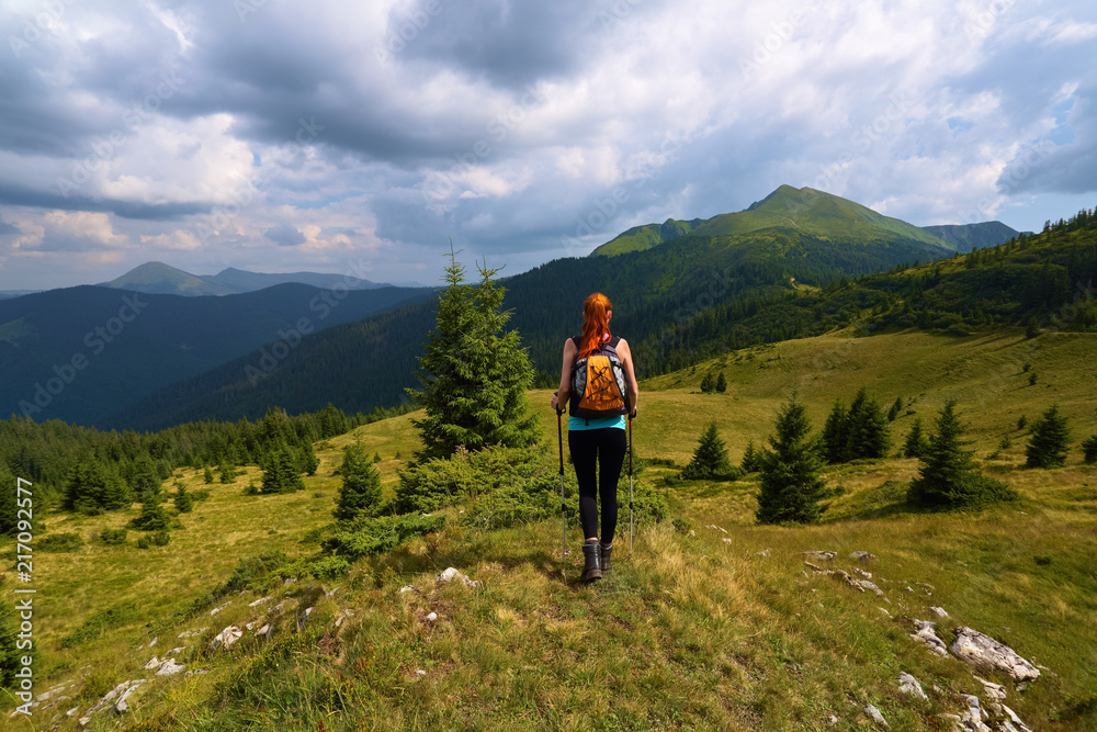 Stormy, thundery sky. The view with the peaks of mountain. Sporty red hair girl climbs up to the hill with rocks. Extreme sport. Unforgettable emotional summer day. Stormy, thundery sky. The view with the peaks of mountain. Sporty red hair girl climbs up to the hill with rocks. Extreme sport. Unforgettable emotional summer day.