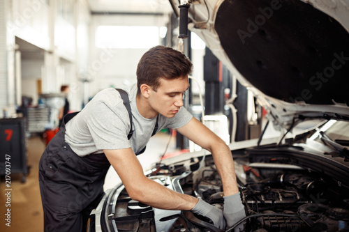 A qualified automachanic is repairing a car at a car service