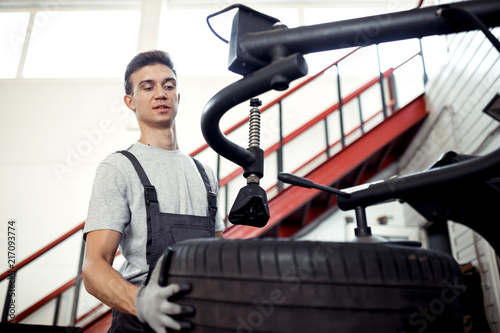 At a car service: a young and attractive guy is checking a tire at work