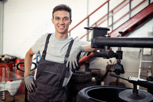 A young and qualified automechanic is smiling while at work during a short break