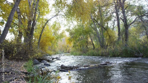 Camera flies from shore over the Provo River at sunset in autumn