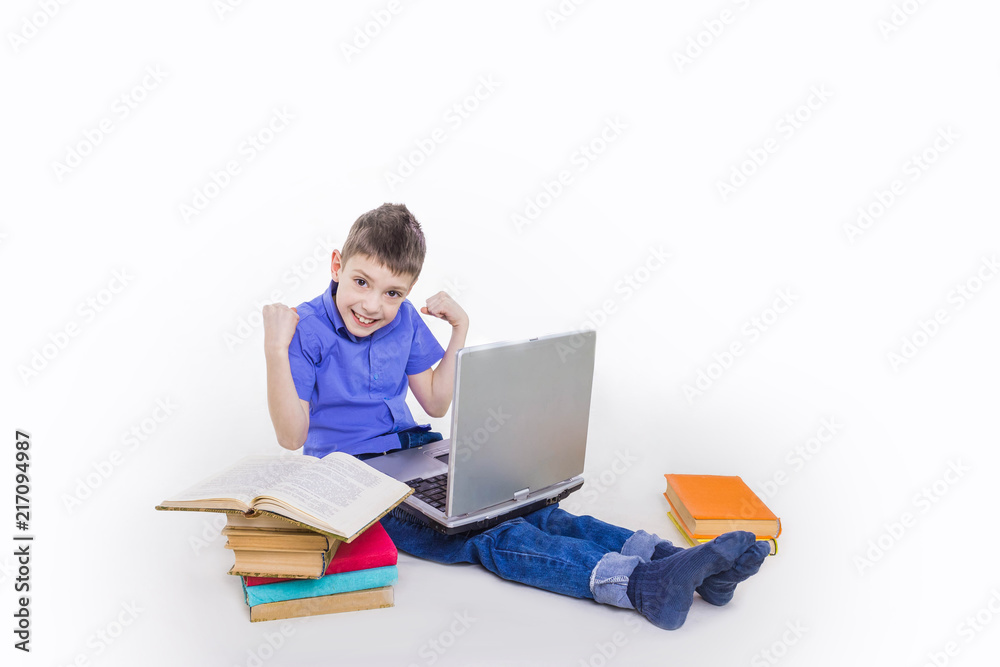 Portrait of cute teen schoolboy sitting near books and typing on laptop keyboard. Happy and surprised little boy, caucasian model isolated on white studio background. Education, study, studying Portrait of cute teen schoolboy sitting near books and typing on laptop keyboard. Happy and surprised little boy, caucasian model isolated on white studio background. Education, study, studying
