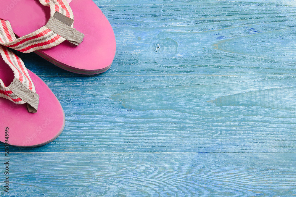 Pink slippers on a blue wooden background, summer background and holiday concept Pink slippers on a blue wooden background, summer background and holiday concept