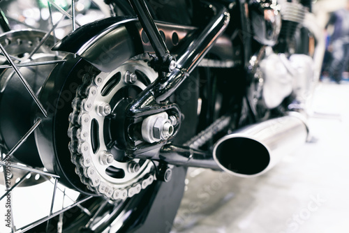 Detail of a motorcycle rear chain with exhaust pipes. Rear view of a motorcycle with the focus on chain..