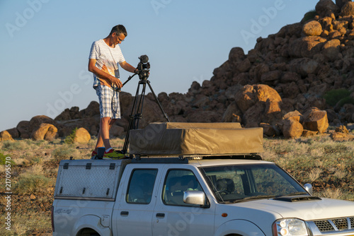 Filmmaker man stay on a car roof