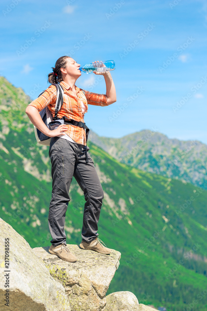 tired tourist on vacation in the mountains drinking clean water from a bottle