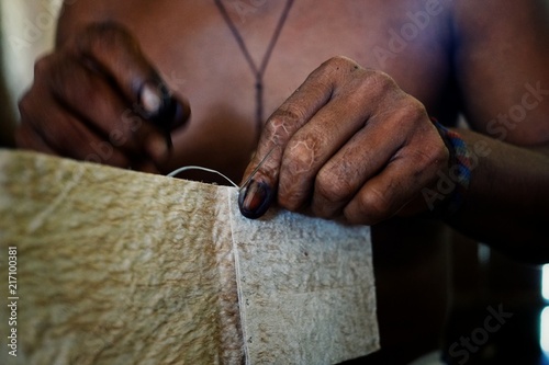 ticuna indian tribal member stitching a tree bark artifact together photo