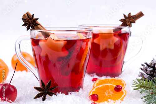 Traditional hot drink at Christmas time. Christmas mulled red wine with spices and fruits. On white snow background