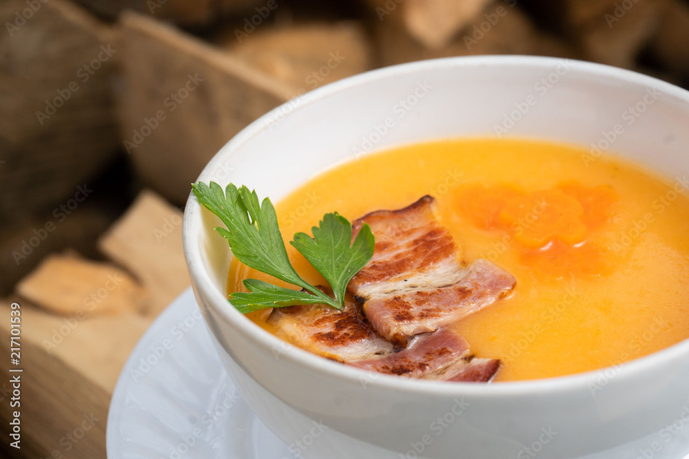 Bowl of pumpkin soup on rustic wooden background. Selective focus