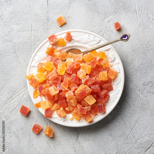 Cubes of dried apricot, mango and papaya on white plate. Candied fruits over gray background. Top view. photo