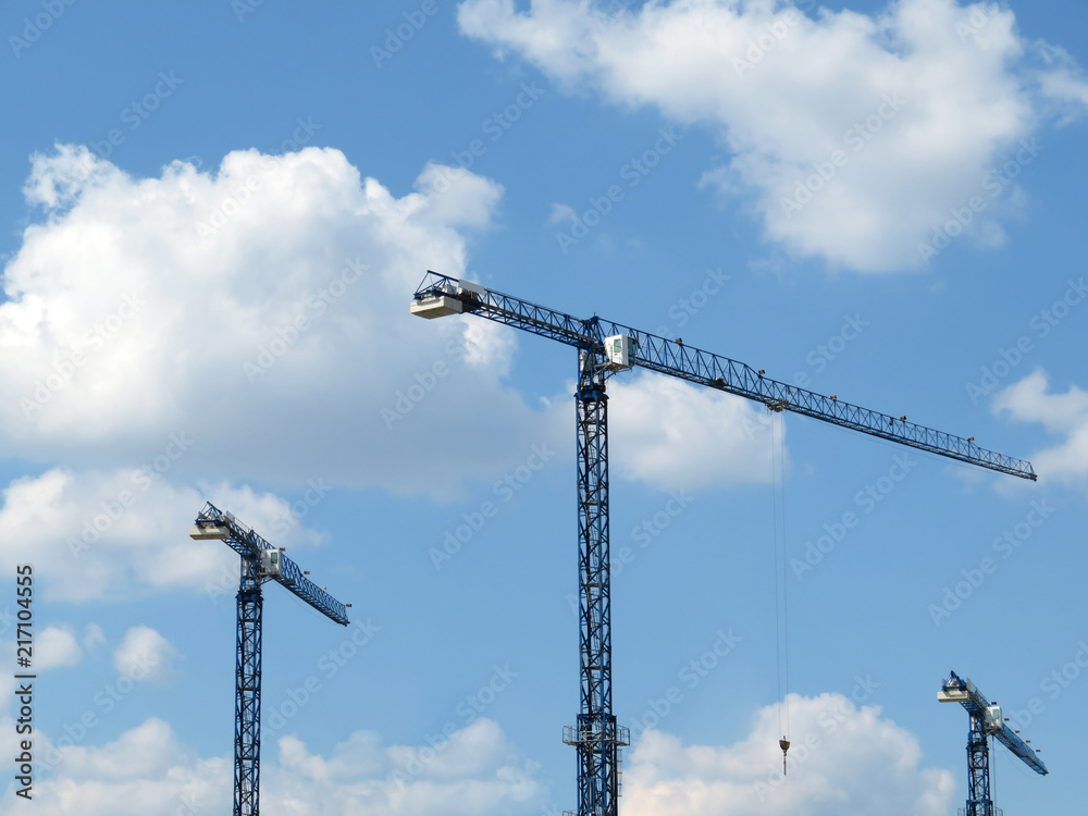 Construction cranes on cloudy blue sky background Construction cranes on cloudy blue sky background