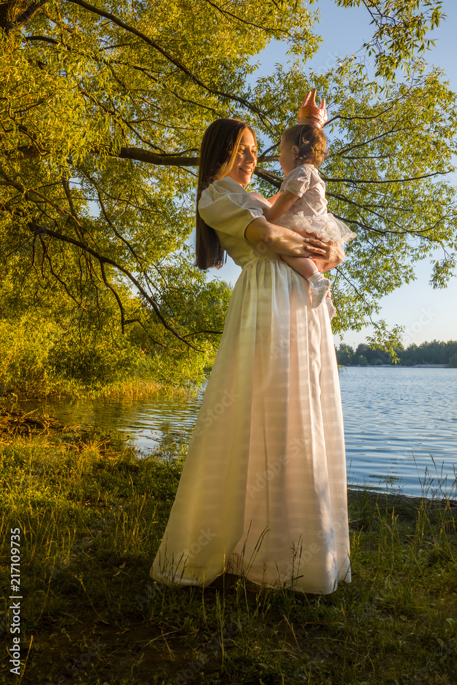 beautiful young mother with a little daughter in the forest at a photo session near the pond